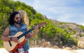 Hippie man playing guitar over island beach Royalty Free Stock Photo