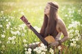 Hippie woman with guitar in summer meadow