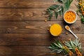 Hippophae juice, branch with berries on wooden table. Fresh sea buckthorn beverage. Flat lay composition, top view