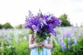 A hippy girl holding bouquet of wildflowers in her hands. Girl hid her face behind bouquet of lupins. Little Girl holds large bouq Royalty Free Stock Photo