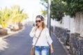 Hippy people portrait with attractive blonde middle age woman walking and calling at the phone on the street in outdoor leisure