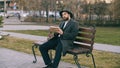 Hipser creative artist man in hat and coat drawing with pen and sketchbook sitting on city street bench at park Royalty Free Stock Photo