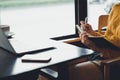 A hipster asian woman working with laptop and writing information into notebook