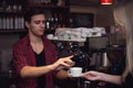 Hipster barista in plaid shirt adds cinnamon