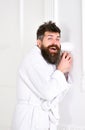 Hipster in bathrobe on surprised face secretly listen conversation. Secret and spy concept. Man in white interior spying Royalty Free Stock Photo