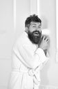 Hipster in bathrobe on surprised face secretly listen conversation. Secret and spy concept. Man in white interior spying Royalty Free Stock Photo