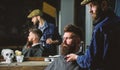 Hipster with beard covered with cape serving by professional barber in stylish barbershop. Grooming concept. Barber busy