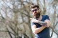 Hipster with beard looks stylish on sunny day. Man with beard and mustache on strict face pointing, nature background Royalty Free Stock Photo
