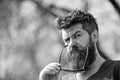 Hipster with beard and mustache on strict face, nature background, defocused. Man with beard looks stylish and confident Royalty Free Stock Photo