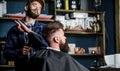 Hipster bearded client getting hairstyle. Barber on cheerful face with hairdryer styling hair of client. Barber with