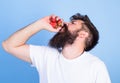 Hipster bearded holds strawberries in fist as juice bottle. Fresh juice concept. Man bearded drinks strawberry juice