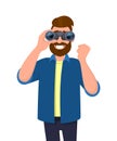 Hipster bearded man in casual wear looking through binoculars and gesturing, making success sign with raised hand fist. Royalty Free Stock Photo