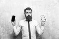 Hipster or bearded man compare mobile phone and smartphone Royalty Free Stock Photo