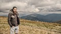 Hipster, bearded man on mountain top on natural cloudy sky