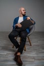 Hipster bearded man with moustache wearing glasses who sitting on chair in studio isolated grey background hold Royalty Free Stock Photo