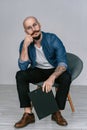 Hipster bearded man with moustache wearing glasses who sitting on chair in studio isolated grey background hold Royalty Free Stock Photo