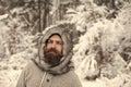 Hipster or bearded man in thermal jacket in snowy forest