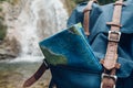 Hipster Blue Backpack, And Map Closeup. View From Front Tourist Traveler Bag On Waterfall Background. Exploring Adventure Hiking C