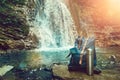 Hipster Blue Backpack, Map And Thermos. View From Front Tourist Traveler Bag On Waterfall Background. Wanderlust Adventure Hiking