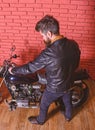 Hipster, brutal biker in leather jacket sits down on motorcycle, rear view. Man with beard, biker in leather jacket near Royalty Free Stock Photo