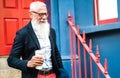 Hipster business man walking with takeaway cup of coffee wall background - Trendy old person wearing casual fashion clothes Royalty Free Stock Photo