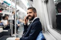 Hipster businessman with smartphone inside the subway in the city, travelling to work. Royalty Free Stock Photo