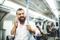 Hipster businessman with smartphone inside the subway in the city, travelling to work. Royalty Free Stock Photo