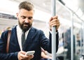 Hipster businessman with smartphone inside the subway in the city, travelling to work. Royalty Free Stock Photo