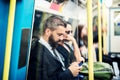 Hipster businessman with smartphone inside the subway in the city, travelling to work. Royalty Free Stock Photo