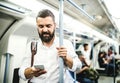Hipster businessman with smartphone inside the subway in the city, travelling to work. Royalty Free Stock Photo