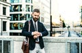 Hipster businessman standing on the bridge in city, checking the time. Royalty Free Stock Photo