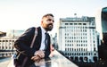 A hipster businessman standing on a bridge in the city, resting. Royalty Free Stock Photo