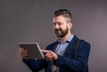 Hipster businessman with tablet, studio shot, gray background