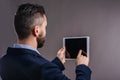 Hipster businessman with tablet, studio shot, gray background