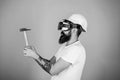 Hipster busy with renovation in virtual reality. Man with beard in VR glasses holds hammer, light blue background