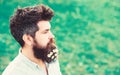 Hipster on calm face, green grass background, copy space. Man with beard and mustache enjoy spring, green meadow Royalty Free Stock Photo