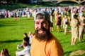 Hipster in cap happy celebrate event fest or festival. Man bearded hipster in front of crowd. Open air concert. Fan zone Royalty Free Stock Photo