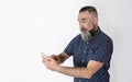 Bearded man of Caucasian appearance, 40-45 years, making a surprised face looking and handling his smarphone Royalty Free Stock Photo