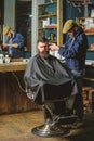 Hipster client getting haircut. Barber with clipper trimming hair on temple of client. Barber with hair clipper works on