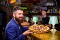 Hipster client sit at bar counter. Man received delicious pizza. Enjoy your meal. Cheat meal concept. Hipster hungry eat Royalty Free Stock Photo