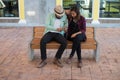 Hipster couple listening music together while sitting on bench a Royalty Free Stock Photo