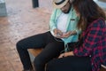 Hipster couple listening music together while sitting on bench a Royalty Free Stock Photo