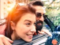 Hipster couple looking outside from their cabrio having fun together - Love and travel concept - Warm light filtered look with