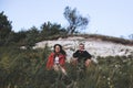 Hipster couple sitting on top of rock mountain in grass and enjoying amazing view on river in sunset. Stylish travelers exploring Royalty Free Stock Photo