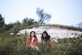 Hipster couple sitting on top of rock mountain in grass and enjoying amazing view on river in sunset. Stylish travelers exploring Royalty Free Stock Photo