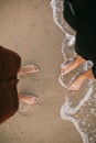 Hipster couple standing walking barefoot on beach, top view. Feet in water foam, summer vacation Royalty Free Stock Photo