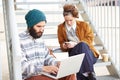 Hipster couple using computer and smartphone outdoors Royalty Free Stock Photo