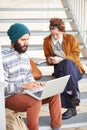 Hipster couple using computer and smartphone outdoors Royalty Free Stock Photo