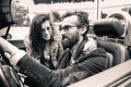 Hipster fashion couple ready for a road trip with a cabriolet roadster car - Young cheerful people smiling and having fun - Royalty Free Stock Photo