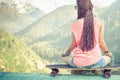 Hipster fashion girl doing yoga, relaxing on skateboard at mountain Royalty Free Stock Photo